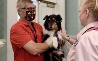 Man holds therapy dog in his arms while talking to an ATD volunteer.