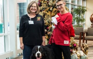 Members of Alliance of Therapy Dogs pose at Christmas tree with dog.