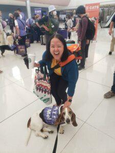 Christina smiles while standing with a certified pup from Alliance of Therapy Dogs.