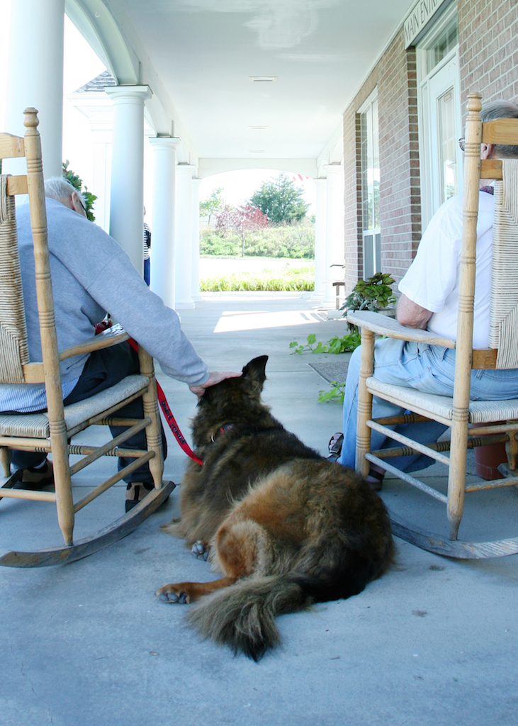 Dog sits between two seniors on rocking chairs.