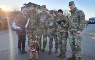 Therapy dog Finlea and her handler pose for a group photo with members of the military.