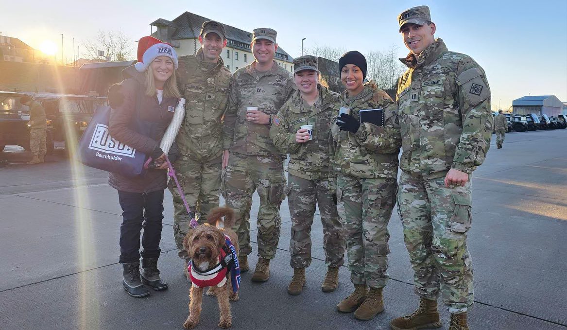 Therapy dog Finlea and her handler pose for a group photo with members of the military.