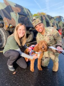Therapy dog Finlea and her handler pose for a photo with military personnel.