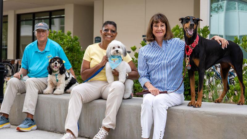 Three tester/observers smiling at the camera with their therapy dogs.