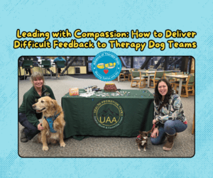 Two ATD teams kneel by a table with their therapy dogs smiling.