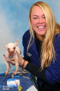 A blonde woman sits holding a chihuahua by a hospital badge