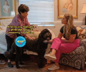 ATD Facility Highlight LightBridge. A woman sits on a bed petting a doodle while speaking with another sitting woman.